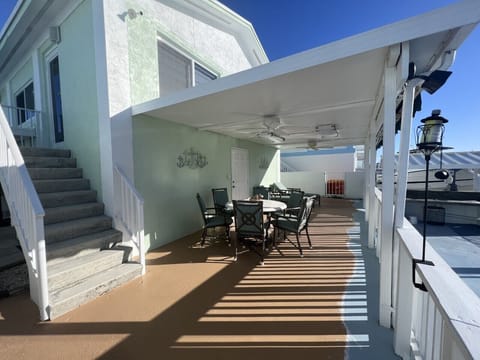 Lounge area downstairs overlooking the water with 2 lounge chairs, table for 6