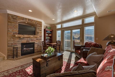 Experience the cozy living room, outfitted with plush seating, an expansive smart TV, and patio doors that frame the breathtaking mountain vistas.