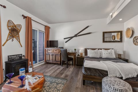 Living Room/Sleeping Space with plush sofa, queen bed (with twin rollaway), work desk, 32" smart tv, private deck access, and full bath access