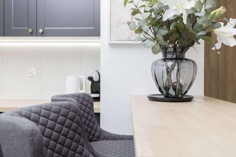 Dining area with gray chairs, floral centerpiece, and light cabinetry.
