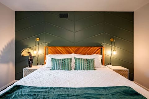 Serene bedroom with bold green accent wall, luxe linens, and warm modern lighting—designed for deep rest.