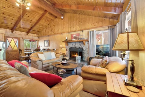 Cozy mountain living room with a stone fireplace, comfy seating, and smart TV—perfect for relaxing evenings, movie nights, and warm cabin vibes after outdoor adventures.