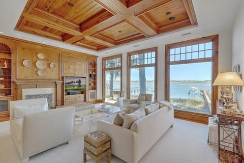 Grand living room area with expansive windows offering panoramic Kiawah River views and plenty of natural light.