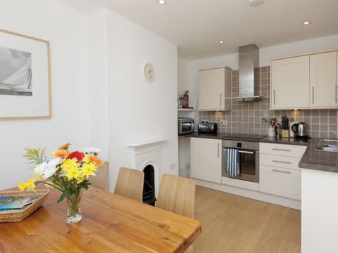 Fully fitted kitchen with dining table and double glass doors to balcony | Quays Cottage, Salcombe