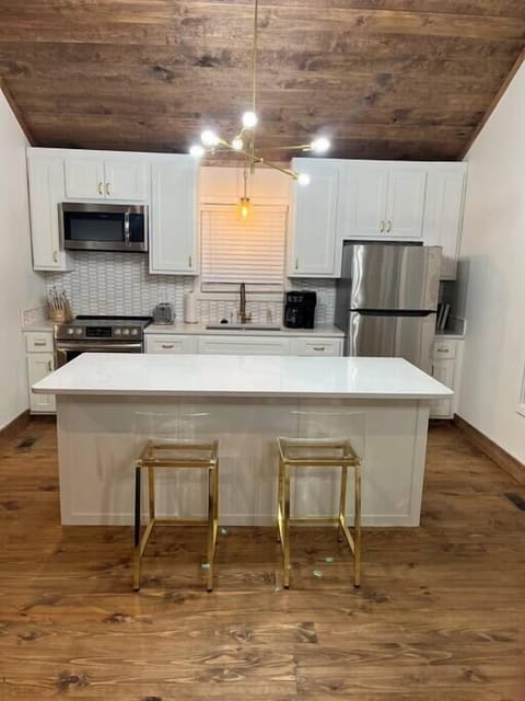 Your kitchen has quartz countertops and island, stainless steel appliances, and gold accent pieces. 