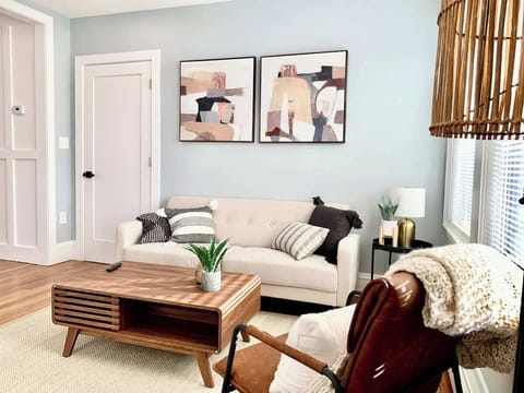Living Room: Front view, comfortable couch next to two large windows that provide tons of natural sun light, alongside with lamps providing soft light. 