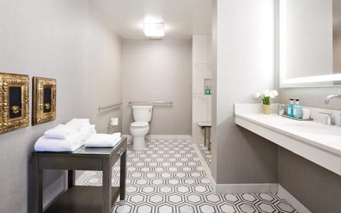 Bathroom with a shower. The essential kit and towels are provided! It features ADA mobility amenities including grab bar attached accessible seating, roll-in shower, lowered vanity in bathroom, and lowered shelf in closet.