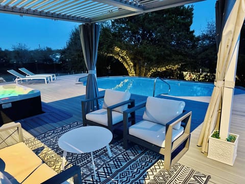 Relaxing hot tub, sparkling pool, and stylish pergola with cozy seating.
