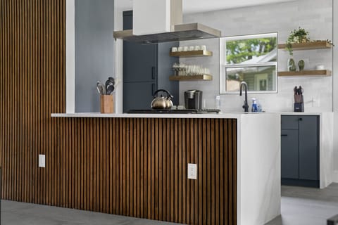 Modern kitchen island with wood accents, quartz counters, and open shelving