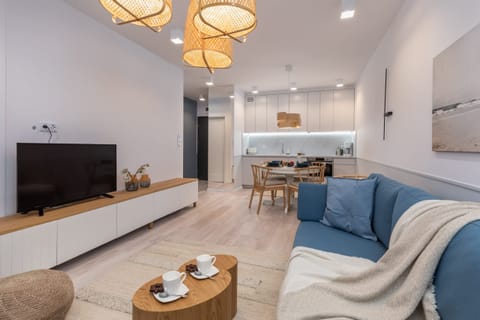 A living room with a cozy blue sofa, a wooden coffee table, and a warm lighting fixture creating a homely ambiance.