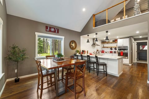 Open dining area beneath vaulted ceilings with wood floors and natural light
