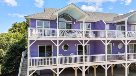 Distinctive purple beach house with multilevel balconies and coastal charm awaits your arrival.