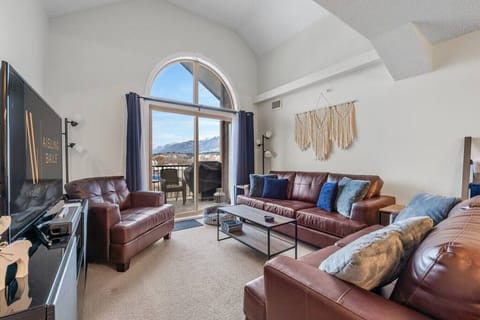 Living room with a Smart TV, walkout access to the top-floor balcony and cozy seating options with a queen pull-out couch (all bedding provided.)