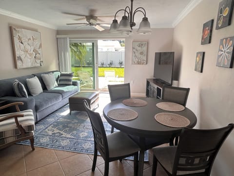 Your stylish living space flows seamlessly from comfortable seating to dining table, with garden views through sliding doors creating a bright, welcoming atmosphere.