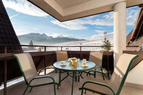 A cozy balcony with a table and chairs, offering a breathtaking panoramic view of the mountains.