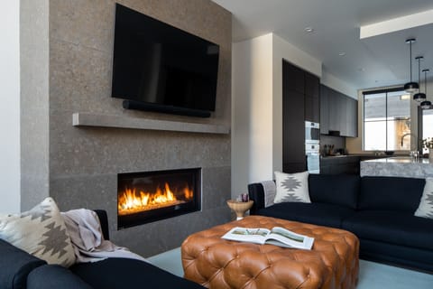 Settle into your stylish living space where modern comfort meets cozy elegance. The warm fireplace creates perfect ambiance while you relax on plush seating and enjoy entertainment on the large TV.