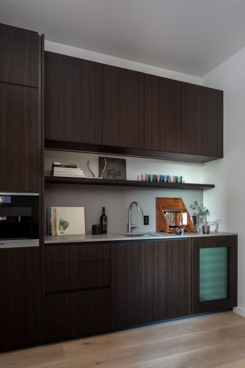 Step into your sleek modern kitchen where dark wood cabinetry meets sophisticated simplicity. You'll love preparing meals with premium appliances and ample storage at your fingertips.