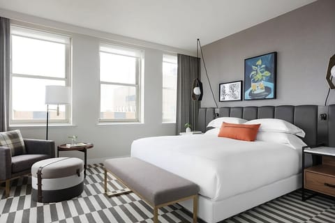 Unwind in crisp linens beside bright windows and cozy seating.