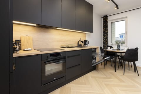 A kitchen with deep black cabinetry paired with wooden accents and modern appliances for a chic look.
