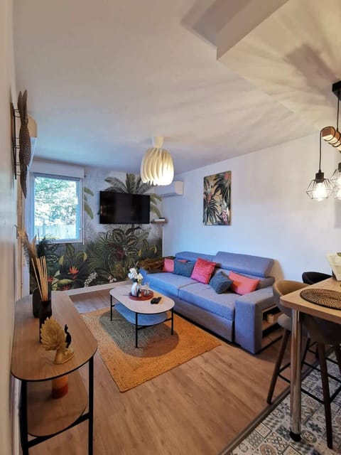 Séjour lumineux avec canapé, coin repas et cuisine ouverte, appartement Le Jungle à Blagnac
