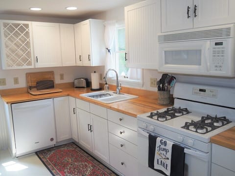 KITCHEN:  Looking into the large and modern kitchen, which includes all appliances (including a dishwasher and a gas range), lots of cupboard and counter space, a "coffee cabinet", and a good supply of cooking and dining utensils.