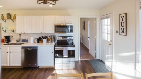 Newly renovated kitchen viewed from dining room. Electric stove, microwave, dishwasher, dual sink, toaster. Backdoor and view to third bedroom