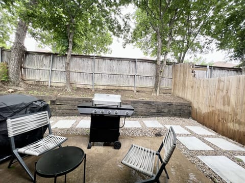 Fenced in backyard w gas grill.