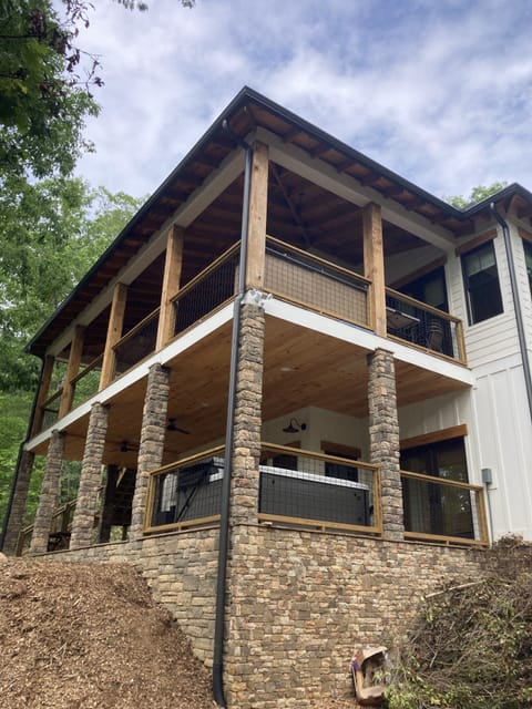 view of back side of house, with hot tub on lower porch level