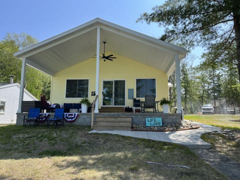 front which looks at the lake, porch with ceiling fan, sectional and table
