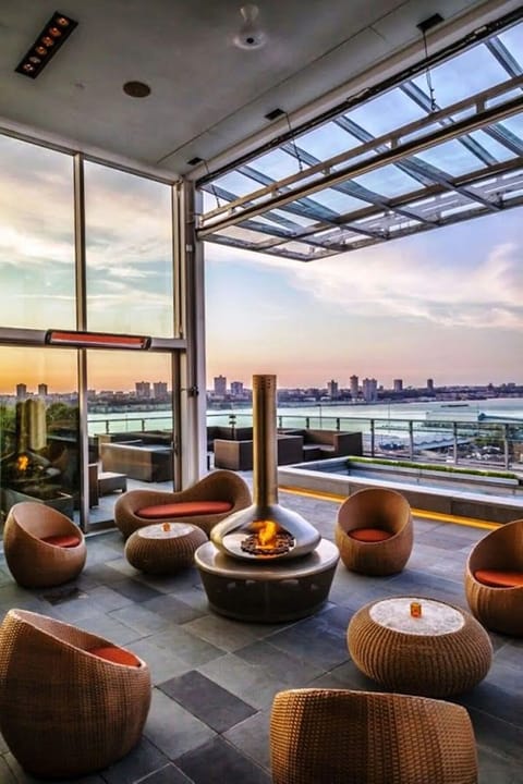 Sip cocktails fireside while sunset city views glow outside.