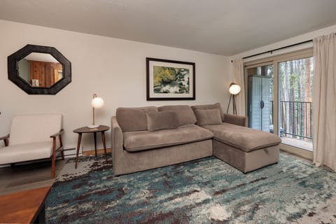 Sink into the plush sectional sofa and unwind in your stylish living space, where natural light streams through the balcony doors.