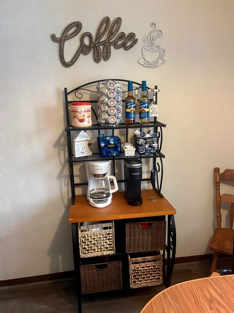 Stocked coffee bar with a single cup Keurig machine, coffee k-cups, hot chocolate k-cups, creamer, and sugar-free flavored syrups.
