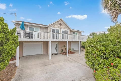 Spacious two story home with elevated balcony, dual garages, and tropical landscaping.