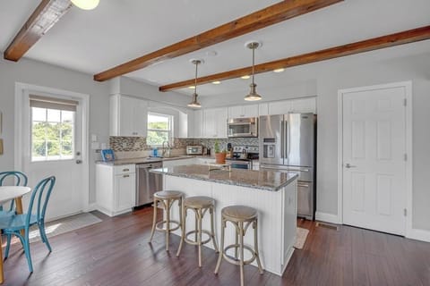 - Kitchen island includes three stools and elegant pendant lights above
- Stainless appliances and white cabinetry create a modern yet beachy feel
- Perfect for cooking, sipping wine, or prepping snacks before beach outings