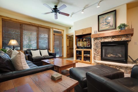 Sink into comfortable leather seating by your stone fireplace, where warm wood accents and mountain views create the perfect retreat.