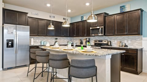 Modern kitchen with granite countertops, dark cabinets, and a spacious island.