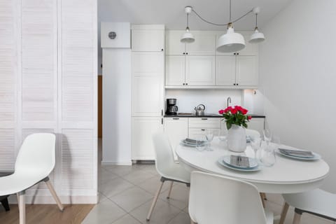 A dining area with a round white table and chairs under modern pendant lights.
