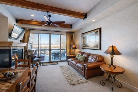 Relax in this mountain-modern sanctuary featuring a plush leather sofa, rustic beam ceilings, and warm lighting. Expansive glass doors offer a seamless connection to your private, scenic balcony.