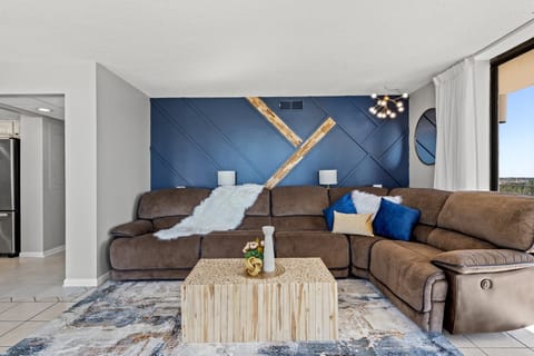 Modern living room with a large sectional sofa and a textured blue accent wall.