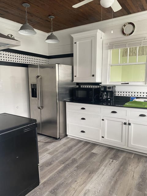 Kitchen has a fridge with ice/water in door, microwave, black stone countertop.