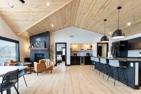 Large island that seats four looking at the coffee/bar nook that includes a 12 cup coffee maker, individual coffee pod and wine fridge.