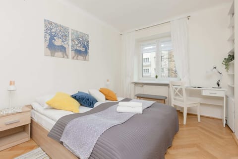 Bright bedroom with a comfortable bed, soft linens, and a desk by the window for work or relaxation.

