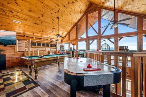 The upstairs loft area includes a game room, (king) bed, full bathroom, bunk beds, large Smart TV, and access to the upper patio deck with lots of seating, a hot tub, and panoramic mountain views.