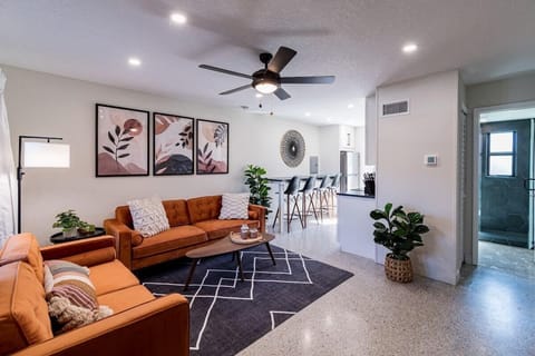 Modern living room with orange sofas and open kitchen seating for four.