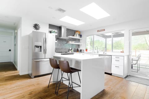 Bright white kitchen with patterned tile backsplash and island seating.