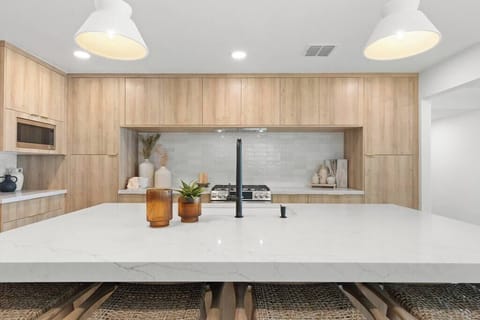 Modern kitchen with a large marble island and wood cabinetry for a clean, inviting space.