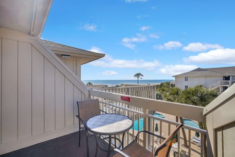 Patio with seating and beach chairs looking out at the ocean and pool.