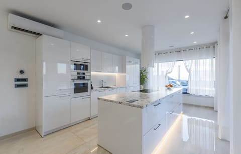 Spacious kitchen decorated in white with a large kitchen island illuminated by LED light