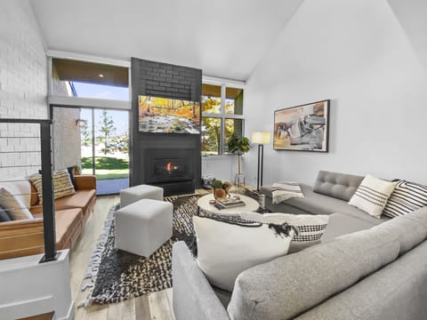 Relax in this cozy, modern living space. Features a warm fireplace, comfortable seating, and access to a patio. Perfect for unwinding.