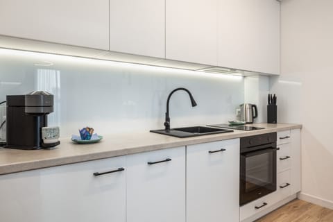 A modern kitchen with white cabinets, built-in appliances, and under-cabinet lighting.